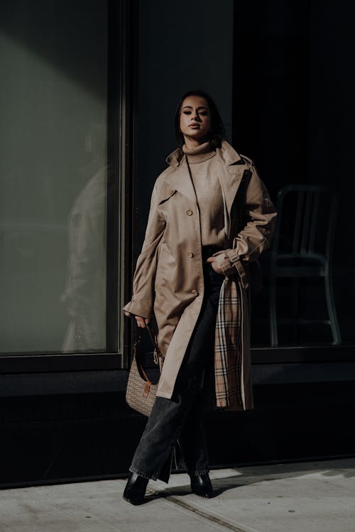 A woman in a trench coat and pants standing outside