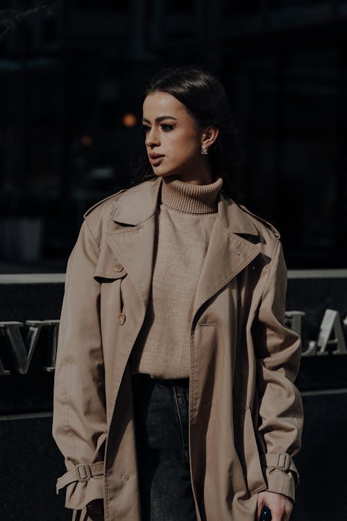 A woman in a trench coat and black turtle neck sweater