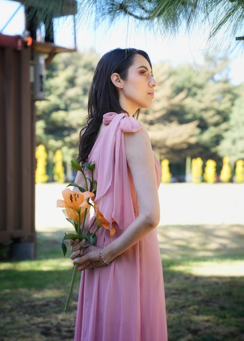 A woman in a pink dress holding flowers