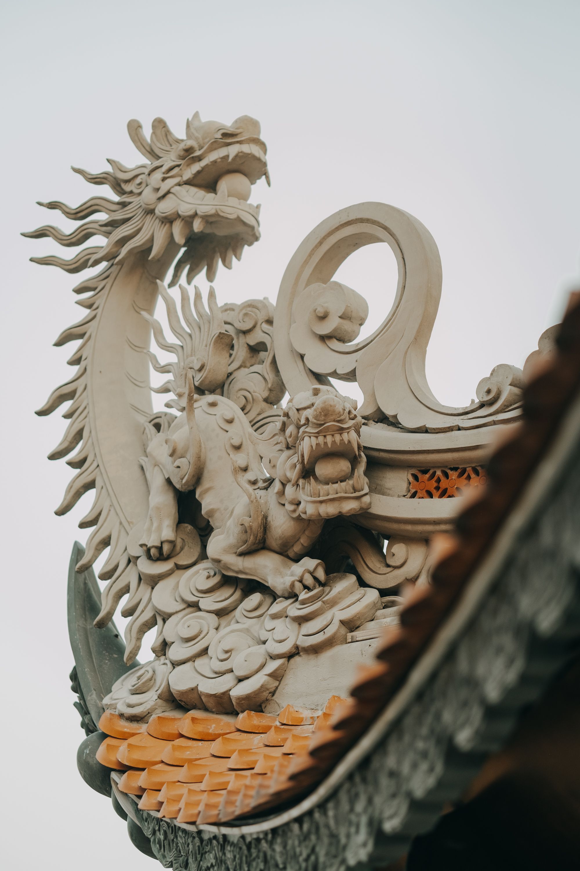 Close-up of a detailed dragon sculpture atop a traditional temple roof.