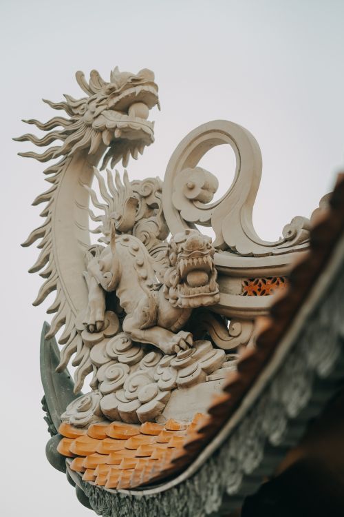 Free Close-up of a detailed dragon sculpture atop a traditional temple roof. Stock Photo