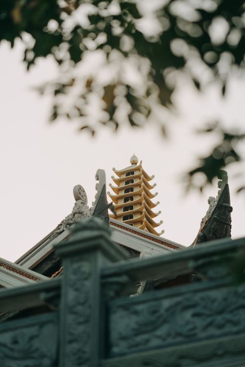Free A beautifully carved temple tower stands tall framed by surrounding leaves, evoking spirituality. Stock Photo