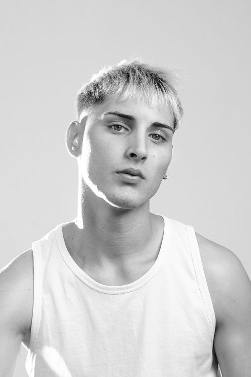 Free Elegant black and white portrait of a young male model in a tank top, exuding a serene and casual vibe. Stock Photo