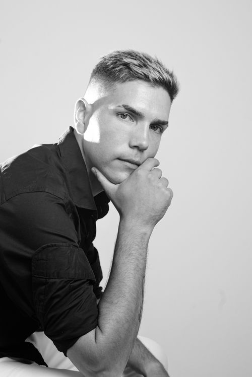 Free Black and white portrait of a man in a studio setting, deep in thought with a hand on his chin. Stock Photo