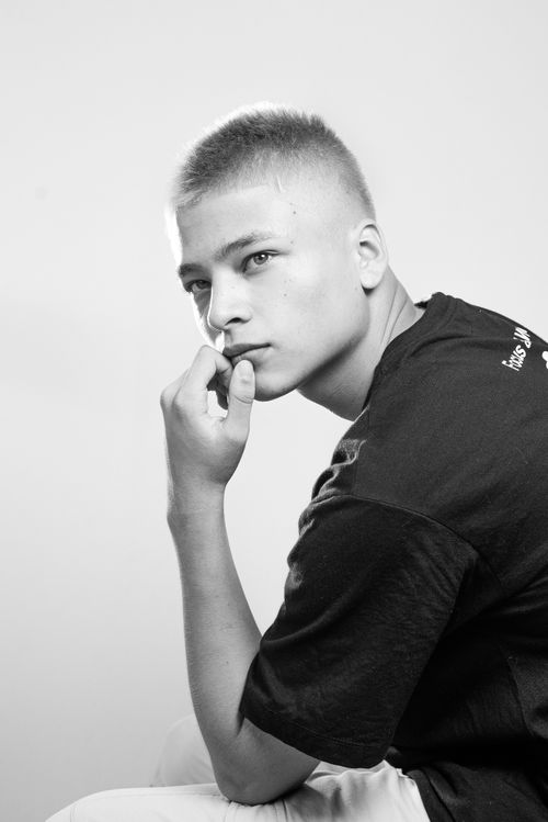 Free Striking black and white portrait of a young man sitting and posing thoughtfully. Stock Photo