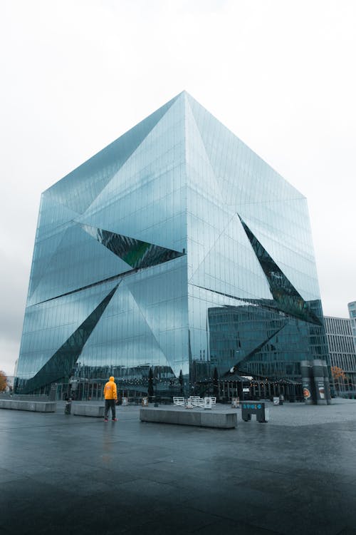 A person is walking in front of a large glass building