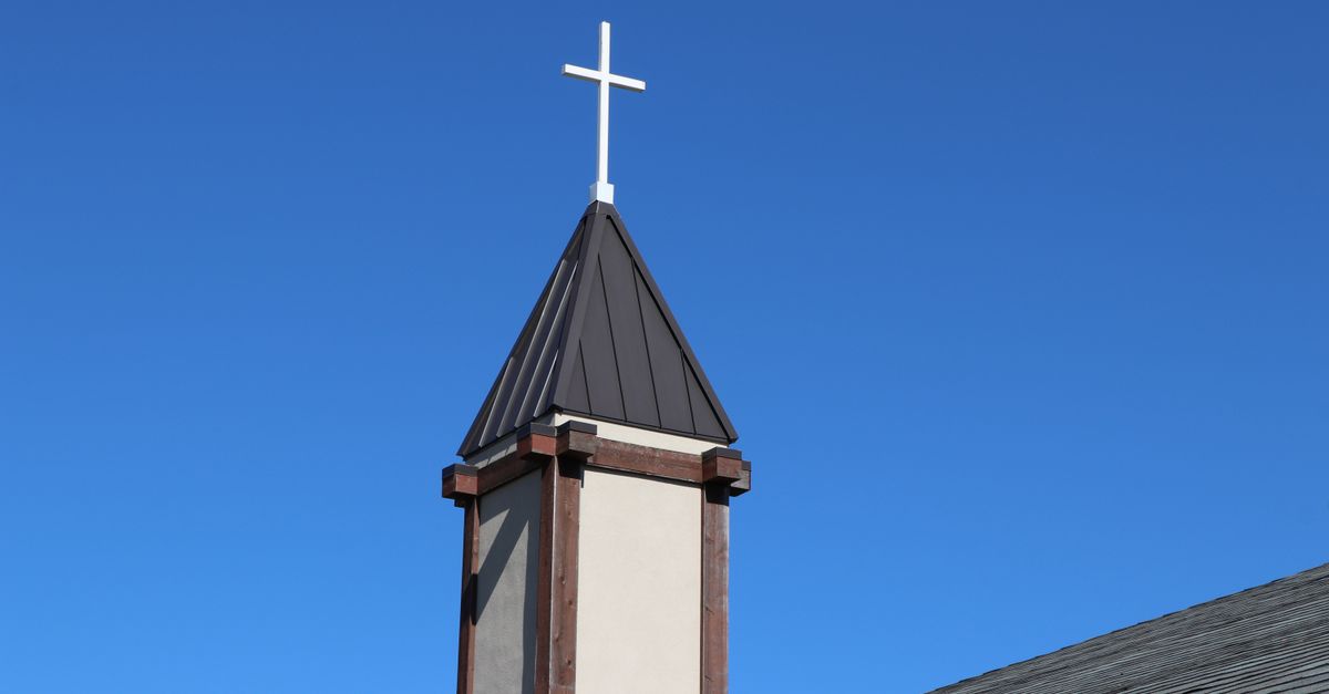 A serene church tower with a cross under a vibrant blue sky in Allen, Texas.