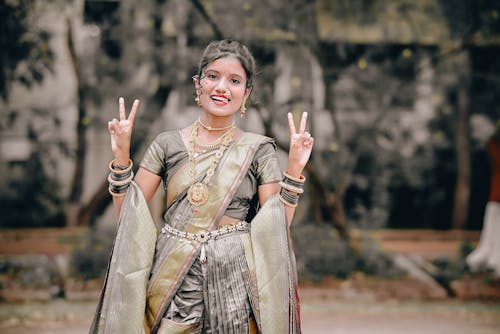 A woman in a traditional sari is making the peace sign