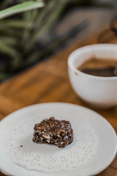 A plate with a piece of chocolate and a cup of coffee