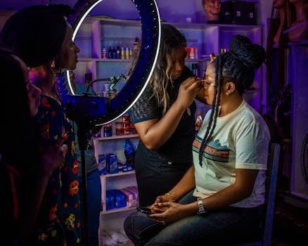 Makeup artist applying cosmetics to a client under studio lighting in Jos, Nigeria.
