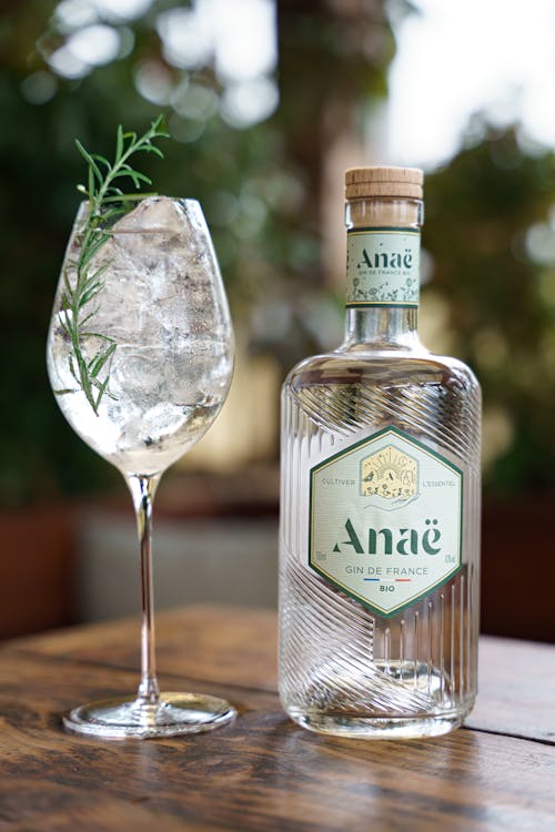 Gin Bottle next to Tall Glass with Ice and Rosemary