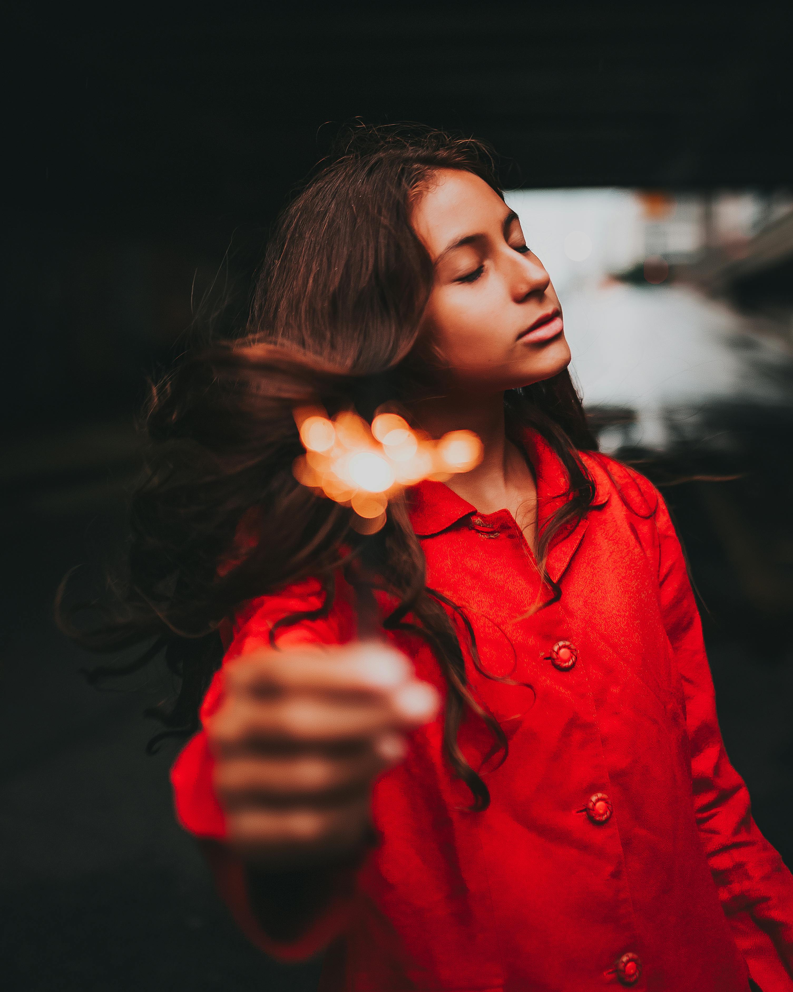 一位身穿红色外套的女子闭目持烟火，神情平静