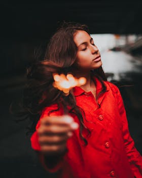 一位身穿红色外套的女子闭目持烟火，神情平静