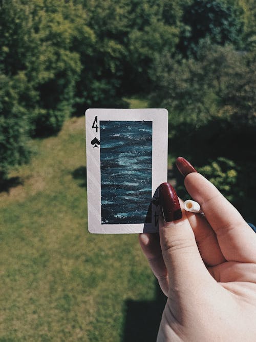 Close-up of a Woman Holding a Card with a Painting and a Cigarette 