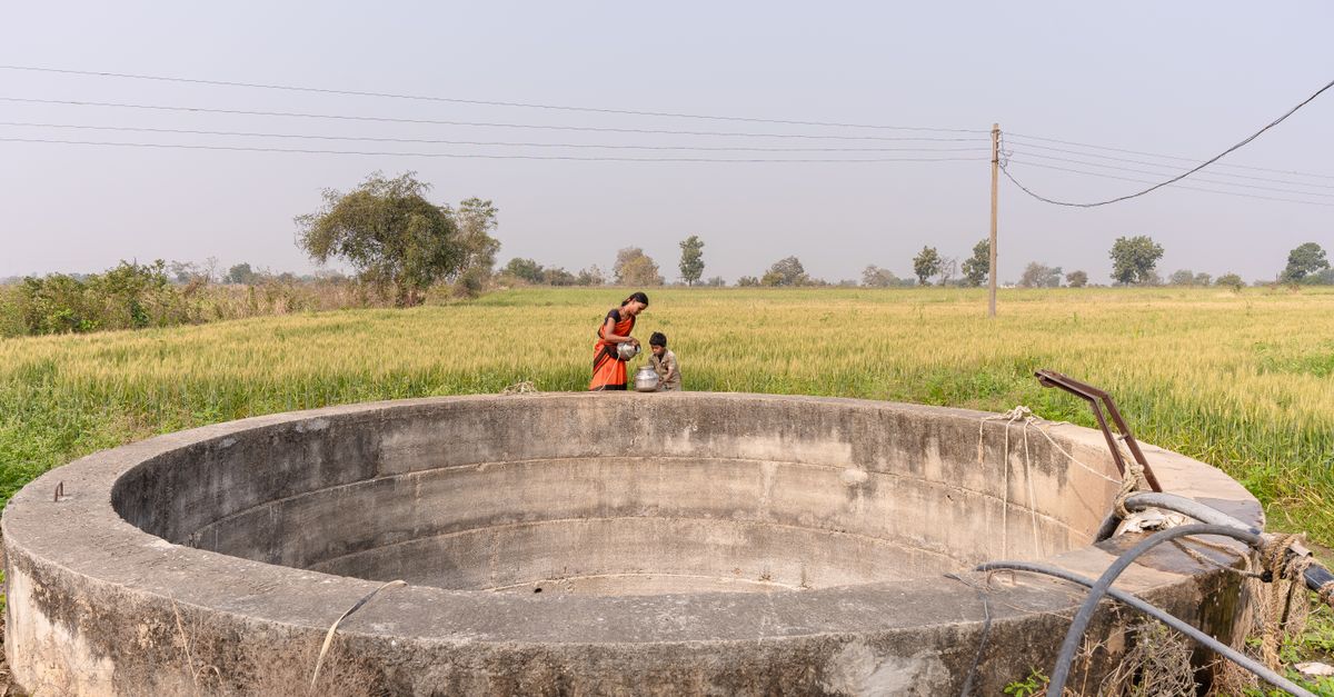 Farmers collecting water from a well in a rural Indian field.