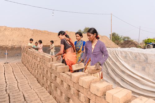 Free Women constructing a brick wall outdoors, symbolizing teamwork in rural settings. Stock Photo