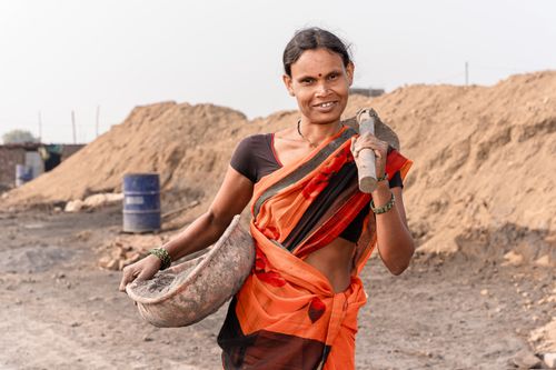 Free A woman in a colorful sari carries a tool, showcasing rural work life in India. Stock Photo