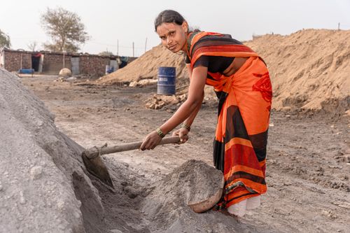 Free Woman in traditional attire working with a shovel in a rural setting. Stock Photo