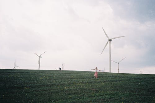 Woman Running in Field with Wind Turbines behind