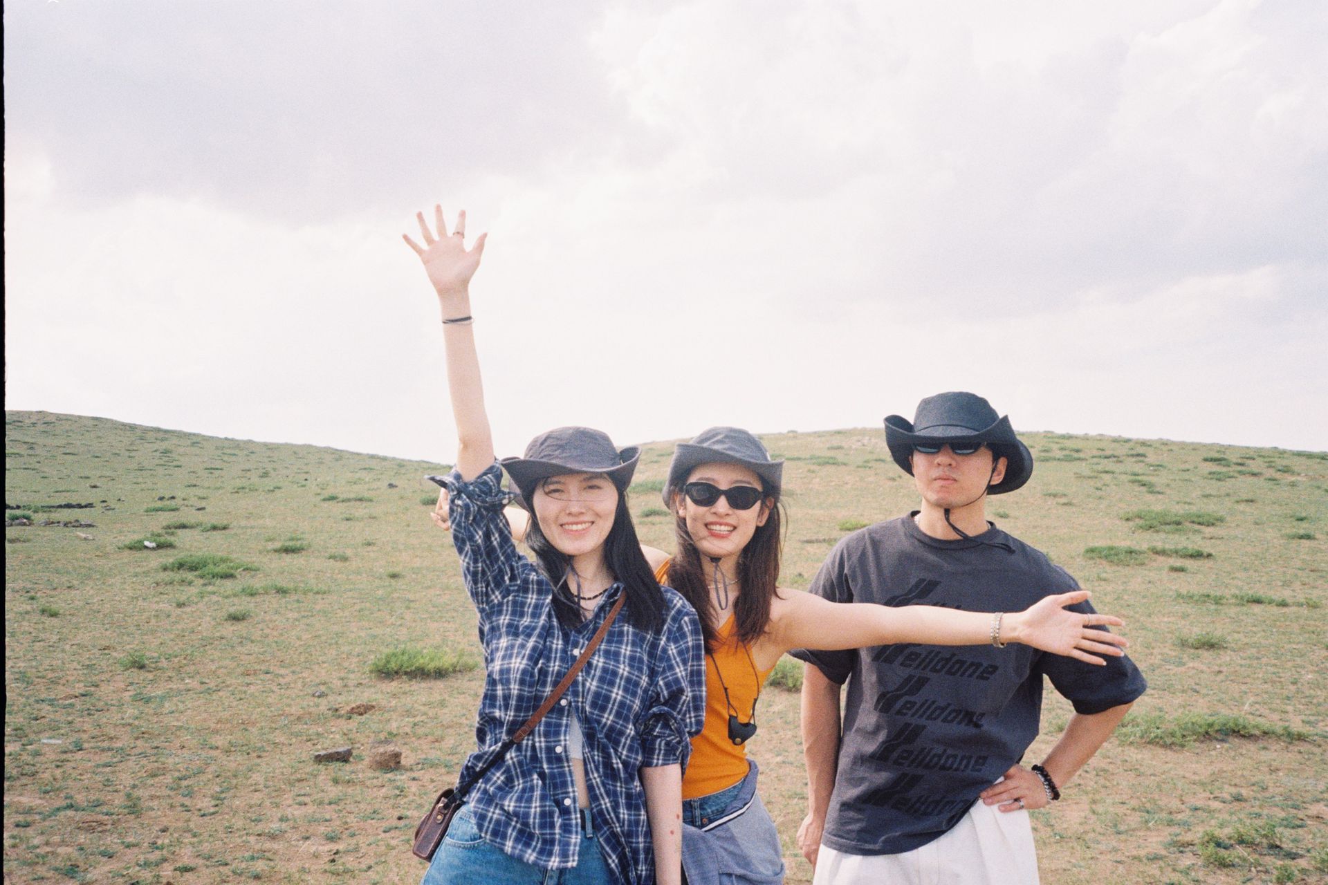 Three friends posing happily in the grasslands of Inner Mongolia, China on a sunny day.