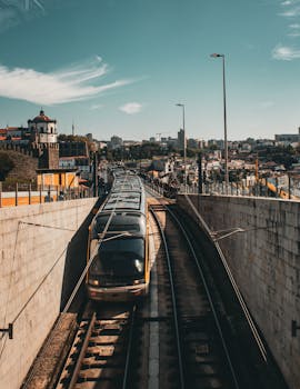 Aerial view of a train exiting a tunnel in Porto, Portugal, showcasing the urban backdrop.