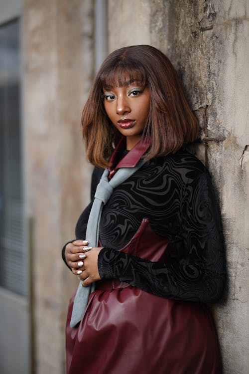 Model in a Burgundy Leather Dress with a Black Patterned Top and a Gray Tie in an Alley