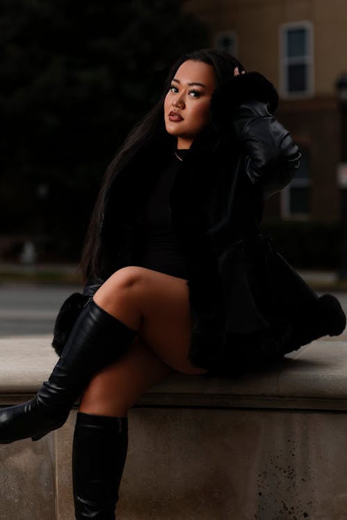 Young Woman in a Black Outfit Sitting Outside 