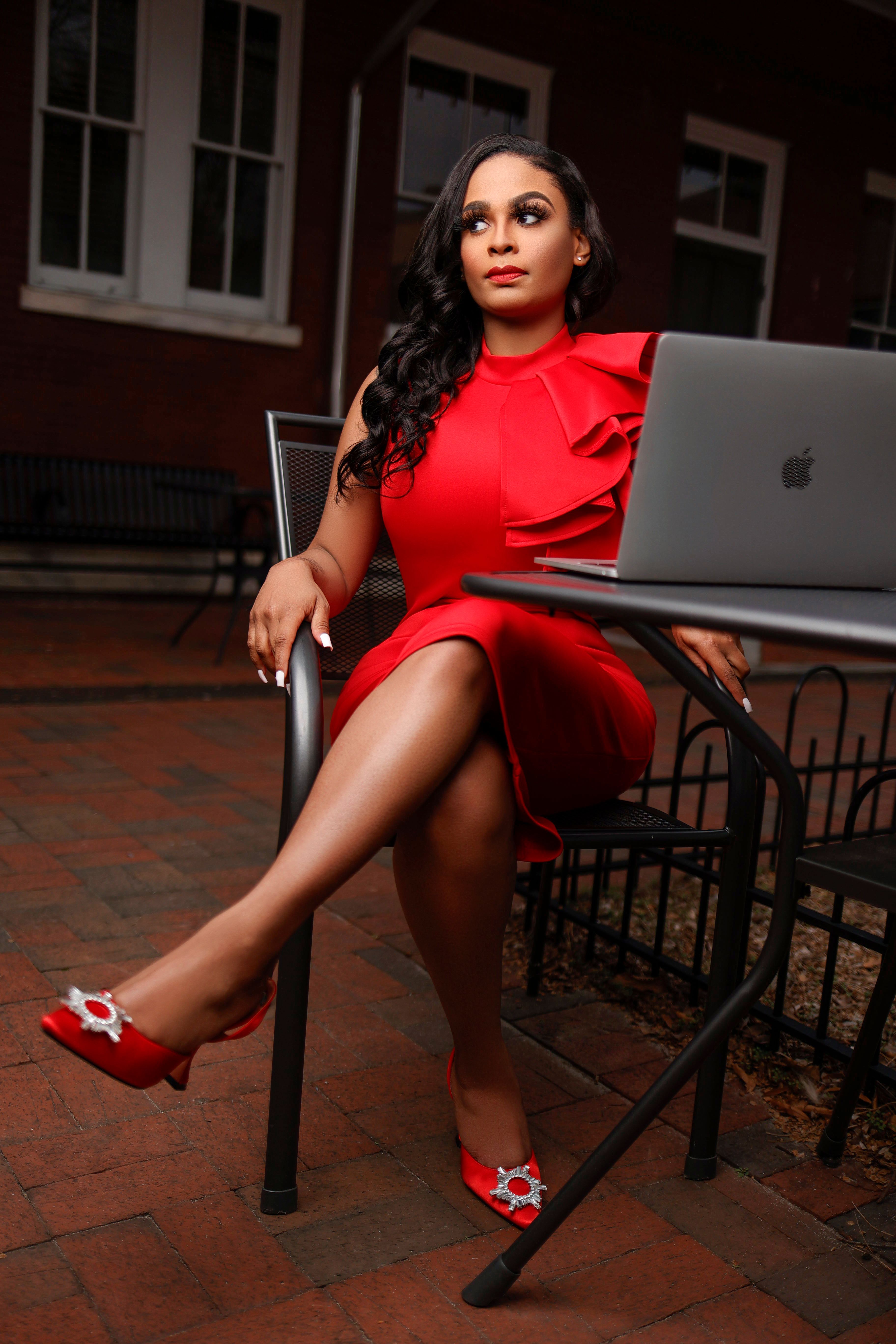 A woman in red dress sitting on a chair with laptop · Free Stock Photo