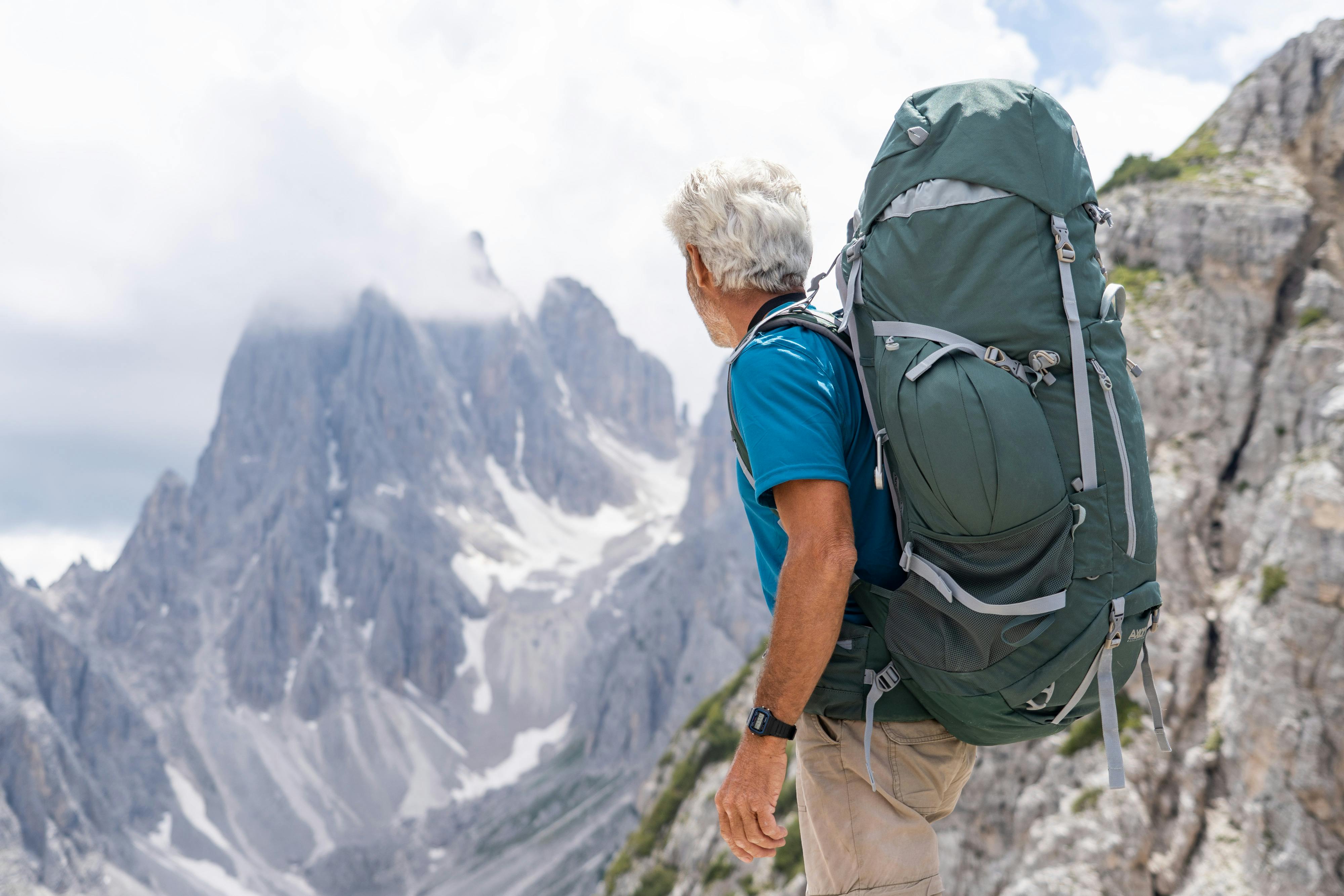 Senior man with backpack hiking through the stunning Dolomites in Italy, enjoying the adventure.