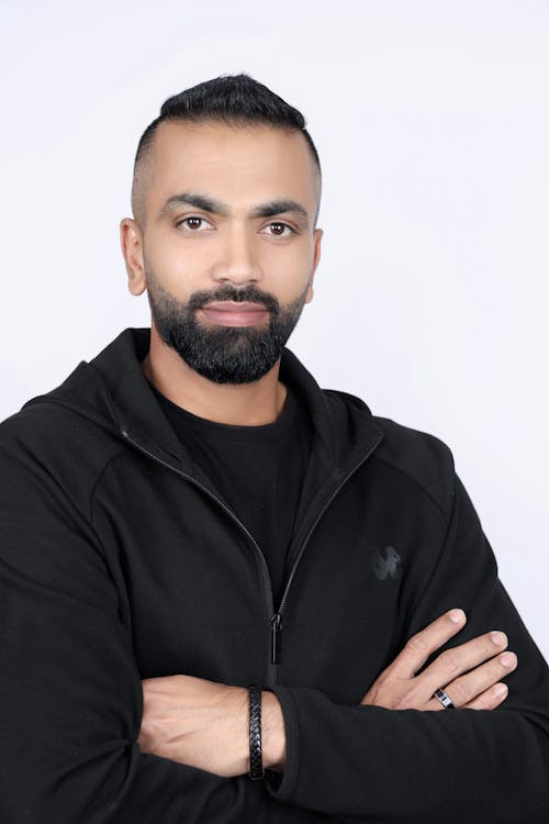 Studio Shot of a Bearded Man in a Hoodie Standing with Arms Crossed 