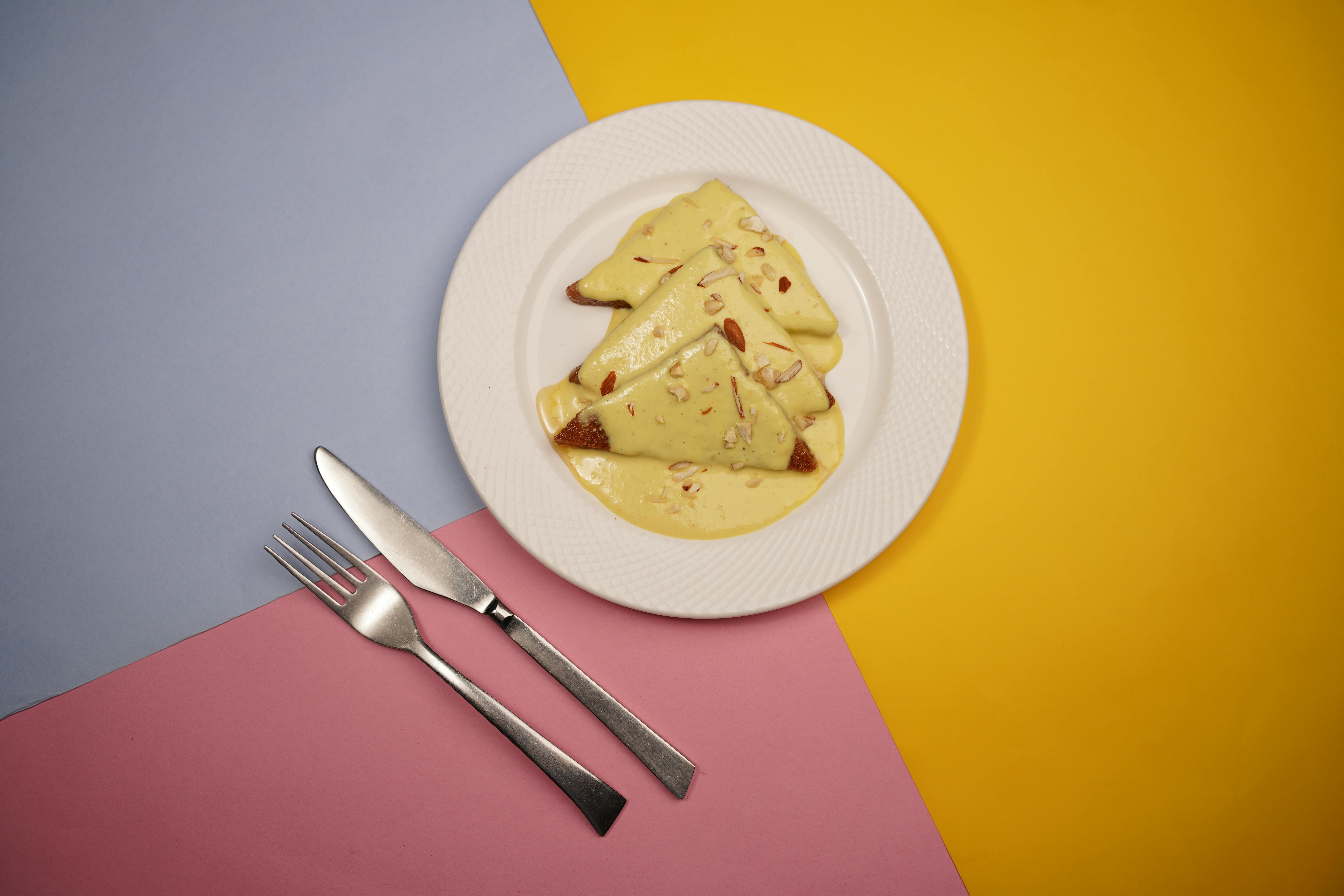 A plate of Shahi Tukda served on a vibrant background with cutlery.