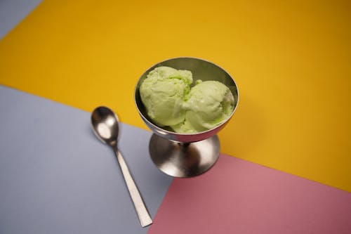 A bowl of green ice cream with a spoon