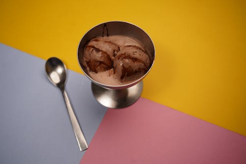 A bowl of ice cream with a spoon on a colorful background