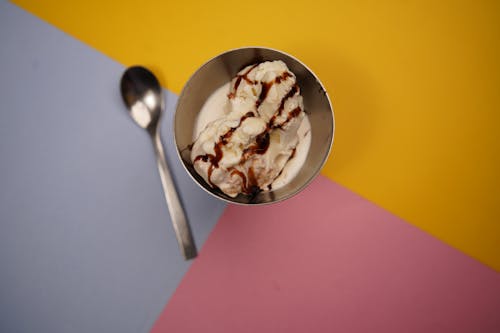 A bowl of ice cream with a spoon and spoon on a colorful background