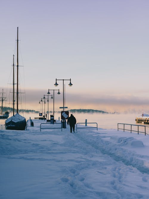 A couple walking on a snowy path near a boat
