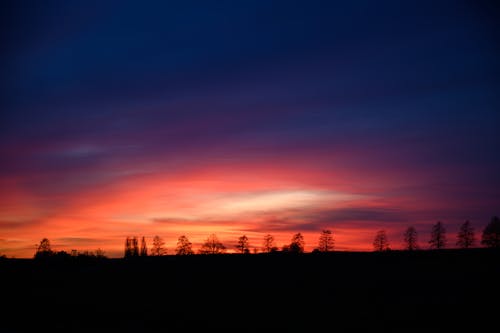 A colorful sunset over a field with trees