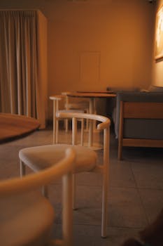 Cozy modern café with minimalist interior featuring chairs and tables in warm lighting.