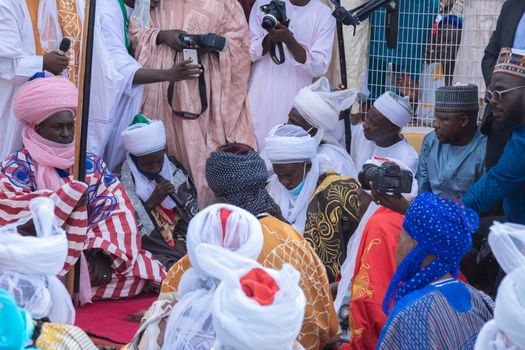 Group of men in traditional attire at a colorful cultural ceremony outdoors.