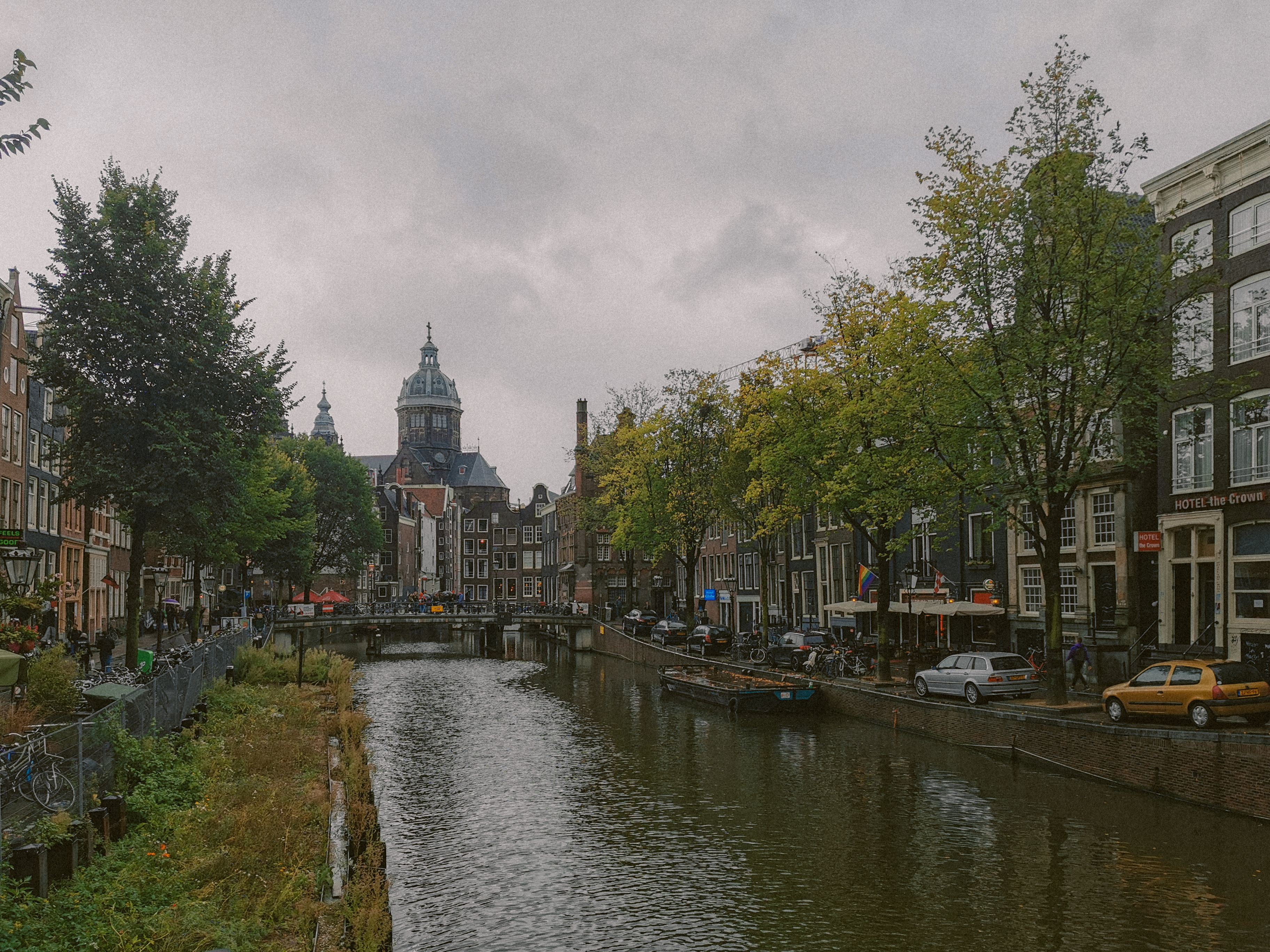 Scenic view of Amsterdam's canal with historic buildings and cathedral on a cloudy day.