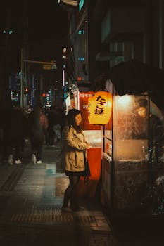 Woman shopping at a street market in the evening under lantern light.