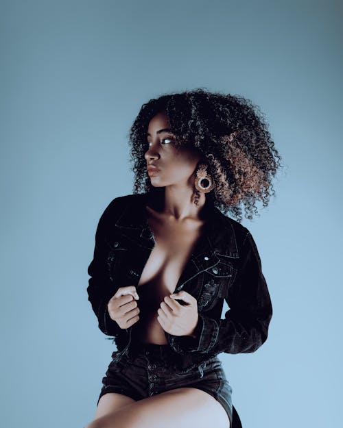 A woman with curly hair posing in a denim jacket