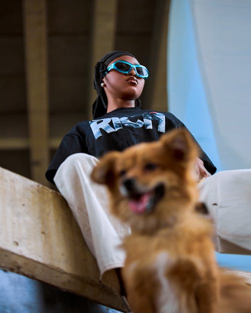A woman in sunglasses and a dog sitting on a ledge