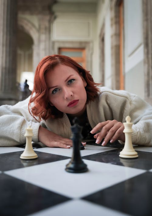 Redhead Model Lying Down with Chess Pieces