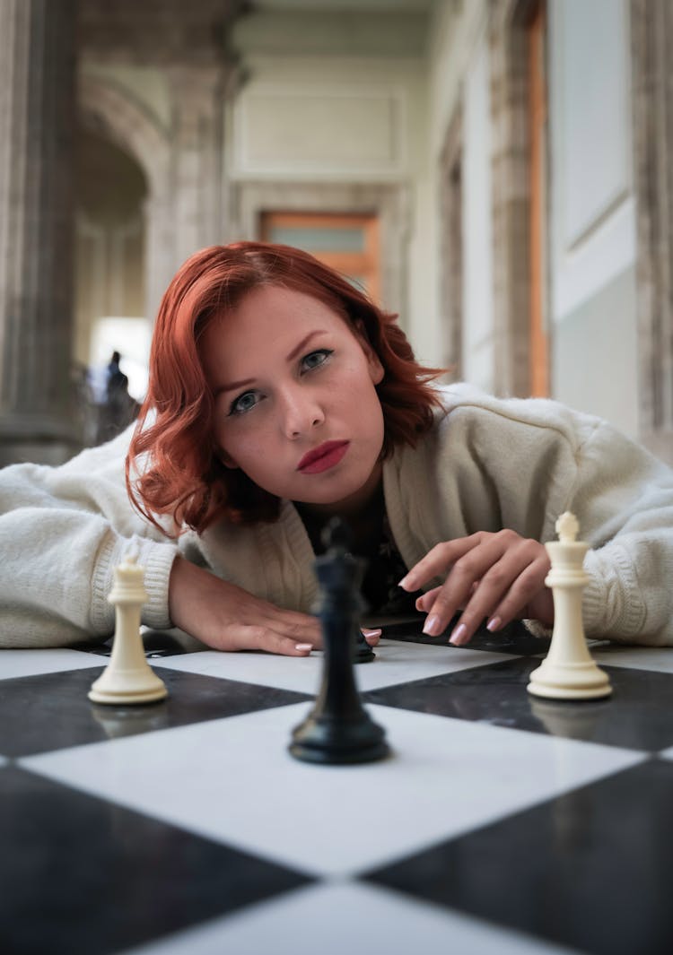 Redhead Model Lying Down With Chess Pieces