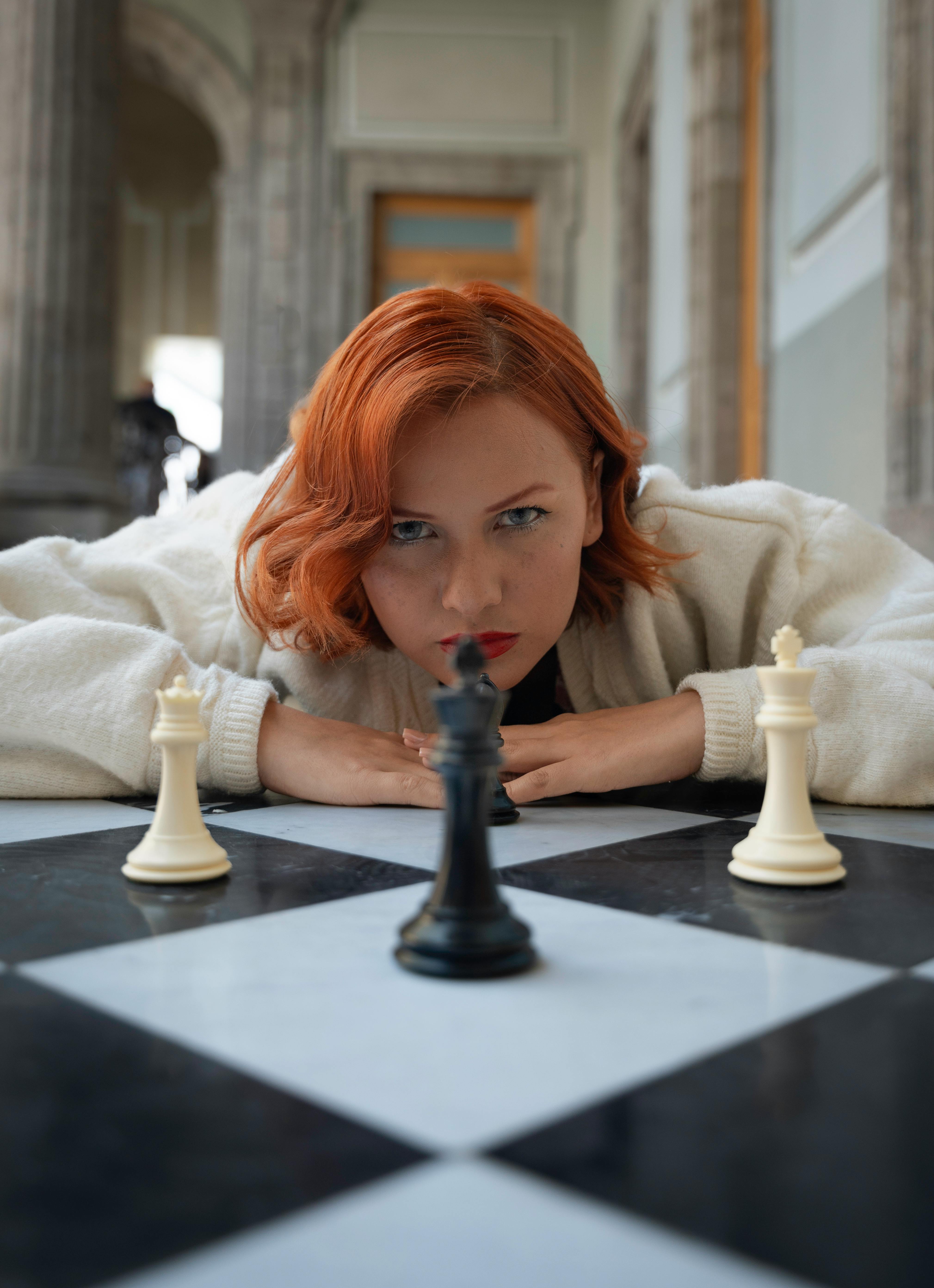 redhead woman lying down with chess pieces