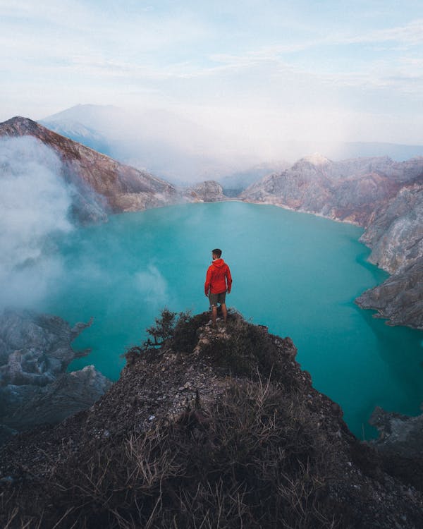 Man in Jacket Standing on Hilltop over Lake