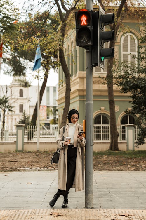Woman Wearing a Coat, Leaning against Traffic Lights