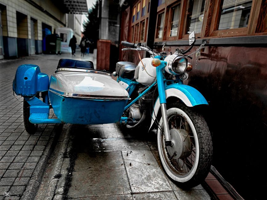 Classic blue motorcycle with sidecar parked on a city street in Eskişehir, Türkiye.