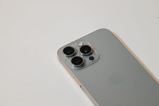 Detailed close-up of a sleek silver smartphone with triple camera lenses, on white background.