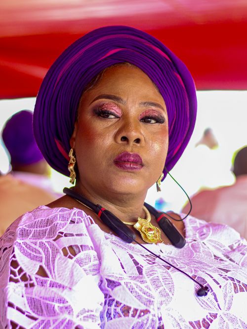 Free Portrait of a woman in traditional attire with purple head wrap and gold accessories. Stock Photo
